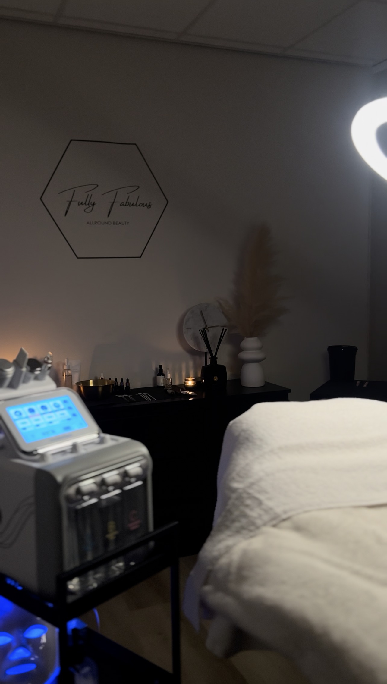 De behandelruimte met het zeshoekige Fully Fabulous bord aan de muur, het HydraFacial-apparaat en de behandelstoel