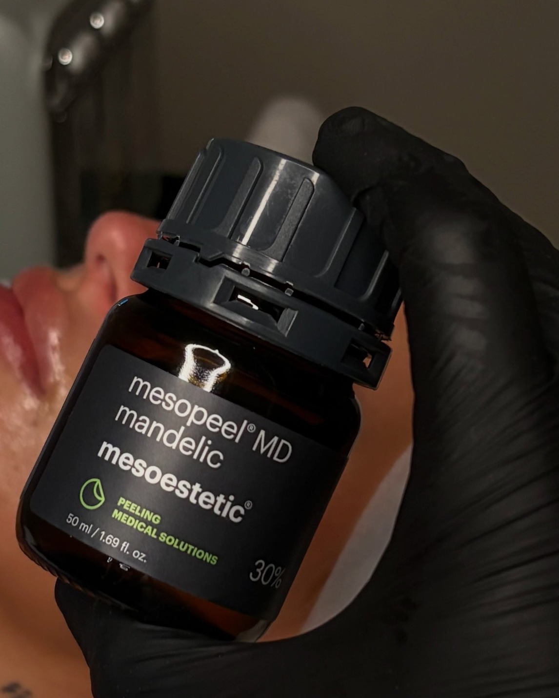 Een flesje Mesoestetic mesopeel mandelic 30% in een gehandschoende hand
